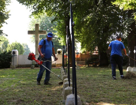Pracownicy Infrastruktura Niepołomice sprzątają cmentarz wojenny w Niepołomicach